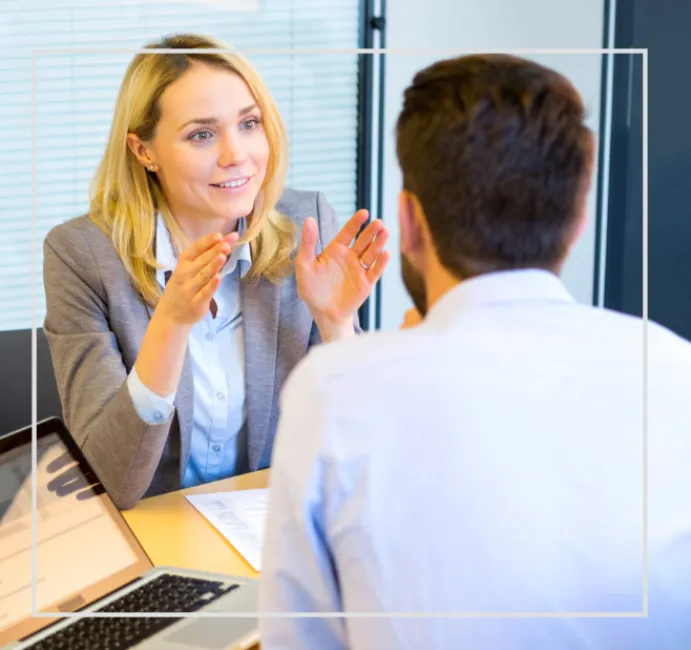 Photographie de deux personnes échangeant autour d'un bureau