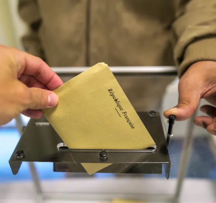 Main glissant un bulletin dans l'urne