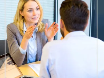 Photographie de deux personnes échangeant autour d'un bureau