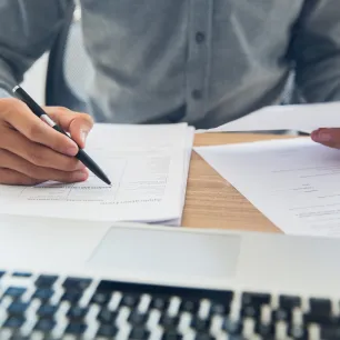 Homme travaillant sur divers documents en prenant des notes