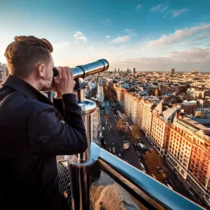 Homme regardant une ville à travers une longue-vue
