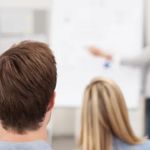 photo de personnes qui écoute une dame devant un tableau