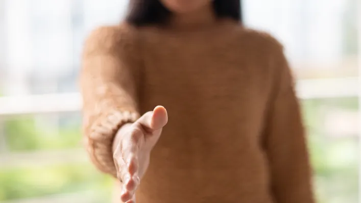 Une femme tend la main en direction de l'appareil photo